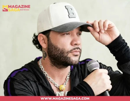 Darey Castro holding a microphone in a black hoodie and white cap, with a DP neck tattoo visible