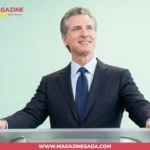 Gavin Newsom standing at a podium in a dark suit, looking upward during a public speaking appearance.