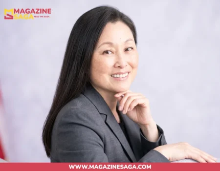 Jennifer Wicks McNamara smiling in a gray blazer with an American flag in the background