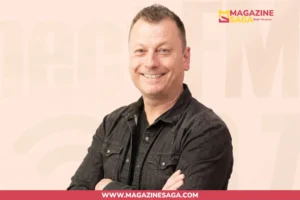 Jimmy Failla smiling with arms crossed, wearing a dark jacket, against a light beige studio background