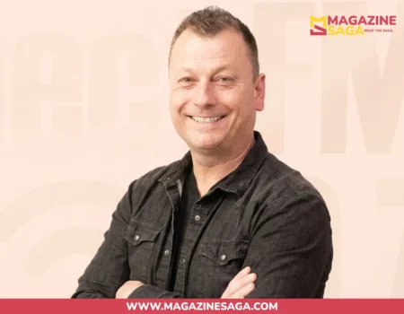 Jimmy Failla smiling with arms crossed, wearing a dark jacket, against a light beige studio background