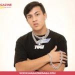 Shane Stoffer known as Togi, wearing a black TOGI shirt and diamond Cuban link chains, arms crossed
