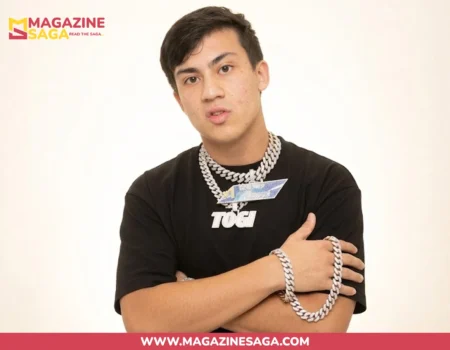 Shane Stoffer known as Togi, wearing a black TOGI shirt and diamond Cuban link chains, arms crossed