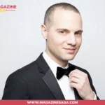 Jordan Roth in a black tuxedo and bow tie, formal studio portrait against a grey background
