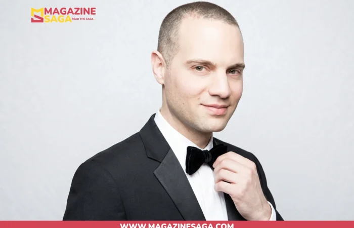 Jordan Roth in a black tuxedo and bow tie, formal studio portrait against a grey background
