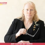 Amy Carter net worth portrait, woman in black blazer with pearl necklace and pins
