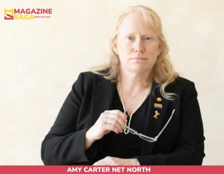 Amy Carter net worth portrait, woman in black blazer with pearl necklace and pins