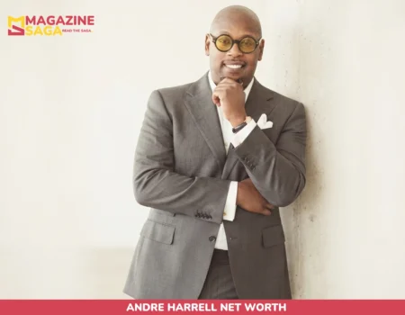 Andre Harrell in gray suit and round glasses, smiling with hand on chin