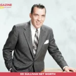 Ed Sullivan net worth photo, man in gray suit leaning on wooden desk smiling