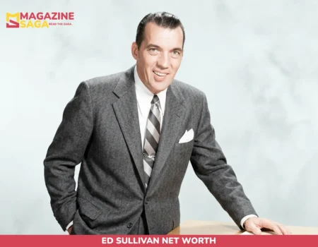 Ed Sullivan net worth photo, man in gray suit leaning on wooden desk smiling