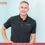 Gary Brecka net worth subject smiling in black Streamline polo against light blue wall