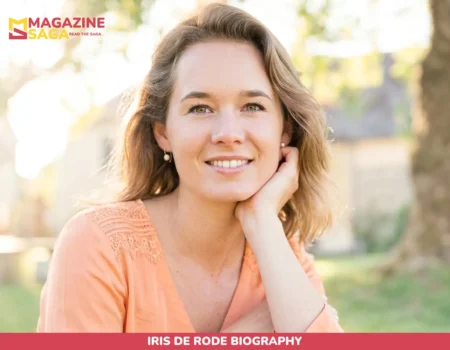Iris de Rode smiling outdoors near a stone building and tree