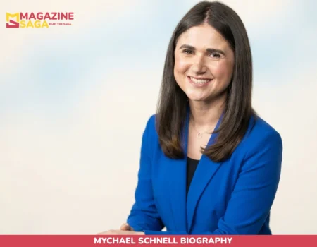 Mychael Schnell biography photo, smiling in blue blazer against neutral backdrop