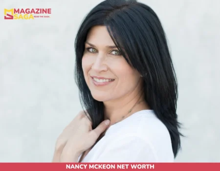 Nancy McKeon net worth portrait, dark-haired woman in white top smiling over shoulder against gray backdrop