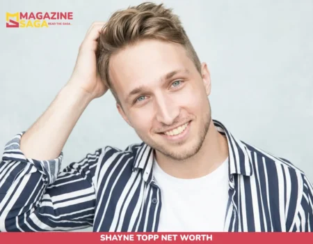 Shayne Topp smiling in striped shirt, hand in hair, studio headshot