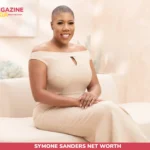 Symone Sanders Net Worth: seated portrait in beige off-shoulder jumpsuit, studio backdrop