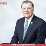 Tom Cole Biography portrait, congressman smiling in navy suit and blue striped tie