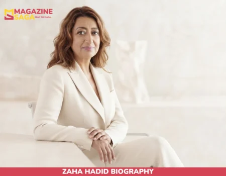 Zaha Hadid biography portrait, seated in cream suit against light backdrop