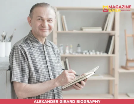 Alexander Girard smiling in checked shirt, sketching in notebook for net worth article