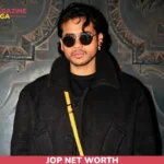 JOP net worth portrait in black coat and sunglasses against carved wall