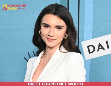 Brett Cooper net worth article portrait, smiling in a white blazer against a blue event backdrop.