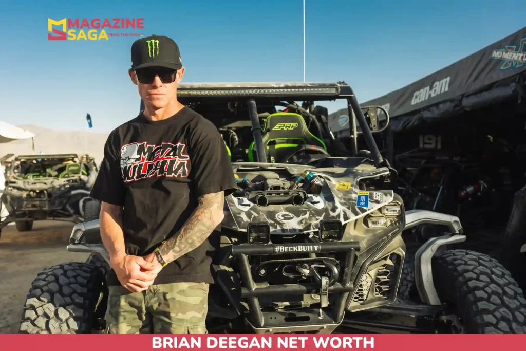 Brian Deegan net worth photo: standing in a Metal Mulisha shirt beside a modified off-road UTV.