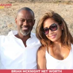 Brian McKnight smiling outdoors beside a woman, arid hills in background, for net worth article