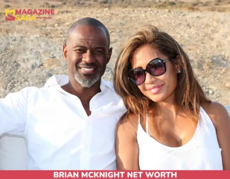 Brian McKnight smiling outdoors beside a woman, arid hills in background, for net worth article