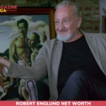 Robert Englund net worth gesturing during a interview, seated beside a vintage diving helmet